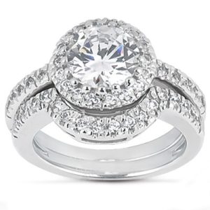 A silver engagement ring features a large round center stone surrounded by smaller stones on the band.