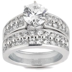A silver engagement ring features a large central diamond surrounded by smaller stones set in two rows.