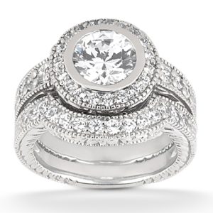 A silver ring set featuring a large circular diamond surrounded by smaller diamonds.