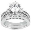 A silver engagement ring featuring a large round diamond at the center, surrounded by smaller diamonds and decorative band detailing.