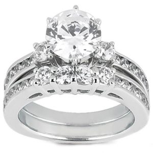 A silver engagement ring featuring a large round diamond at the center, surrounded by smaller diamonds and decorative band detailing.