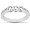 A silver ring features three prominent gemstones set in a row, with smaller stones along the band.