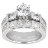 A silver engagement ring with a central round diamond and multiple square-cut diamonds surrounding it.