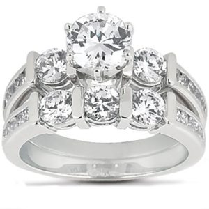 A silver engagement ring features a large round diamond at the center, surrounded by smaller diamonds on the band.