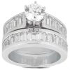 A silver engagement ring and wedding band set features a central round diamond surrounded by baguette-cut diamonds.