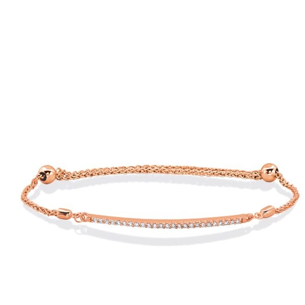 A rose gold bracelet features a thin chain with a line of small clear stones set along the center.
