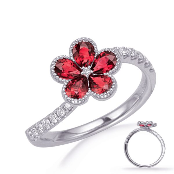 A silver ring featuring a flower design with red gemstones as petals and small clear stones on the band.