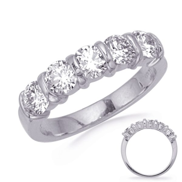 A silver ring features five round, clear gemstones set in a polished band, with a second ring partially visible beside it.