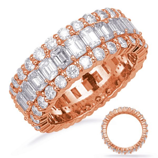 A rose gold ring with multiple rows of round and emerald-cut diamonds is prominently displayed alongside a smaller matching ring.