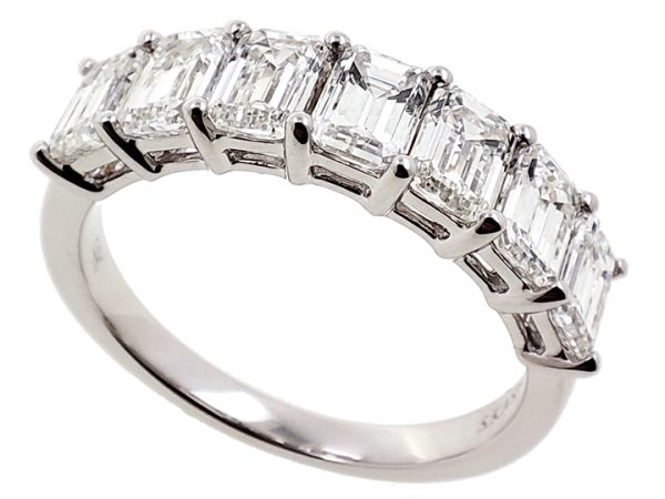 A silver ring features a row of rectangular, clear gemstones set in a pronged design.