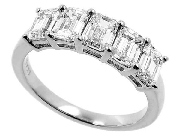 A silver ring features five emerald-cut diamonds set in a row.